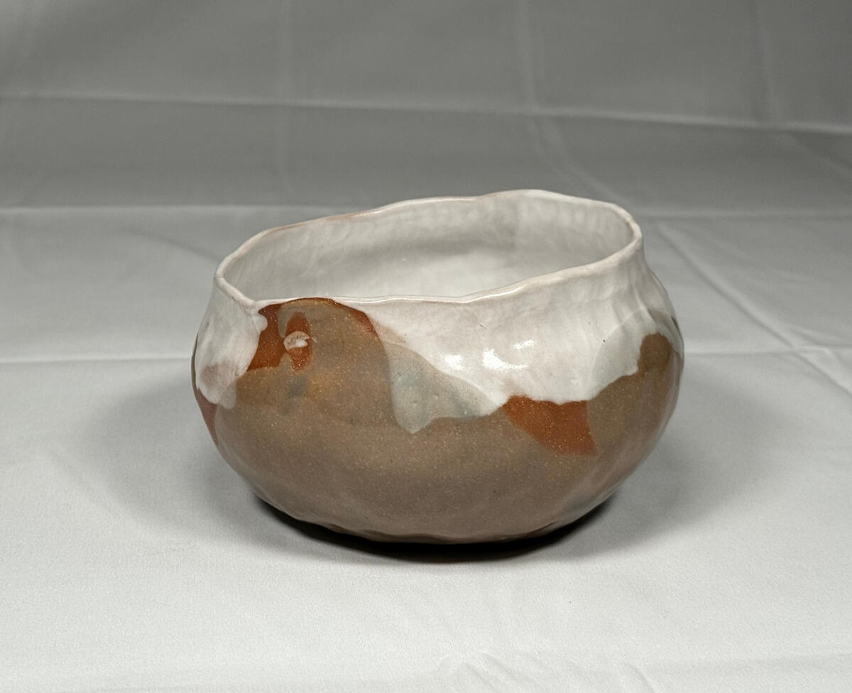 Dimpled, hand-built, light green glazed stoneware bowl by Shane Brodie. This wide, shallow, flat-bottomed bowl has a white liner glaze and a few red clay spots that were left unglazed.