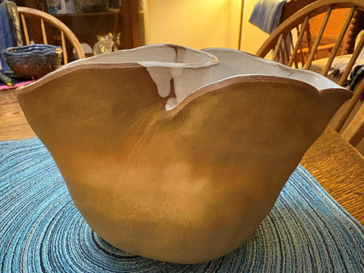 Large stoneware vase with two widely flared openings with wavy rims by Shane Brodie. The yellowish stoneware clay is left unglazed on the exterior, and the interior is glazed with a white liner. Between the openings, there are curved striations.