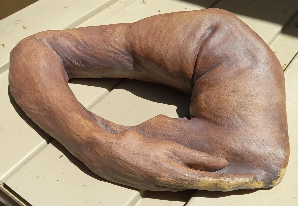 Ceramic sculpture of an arm wrapping around and resting on the back of a neck by Shane Brodie. Surface texture shows gestural finger marks emphasized with iron oxide.